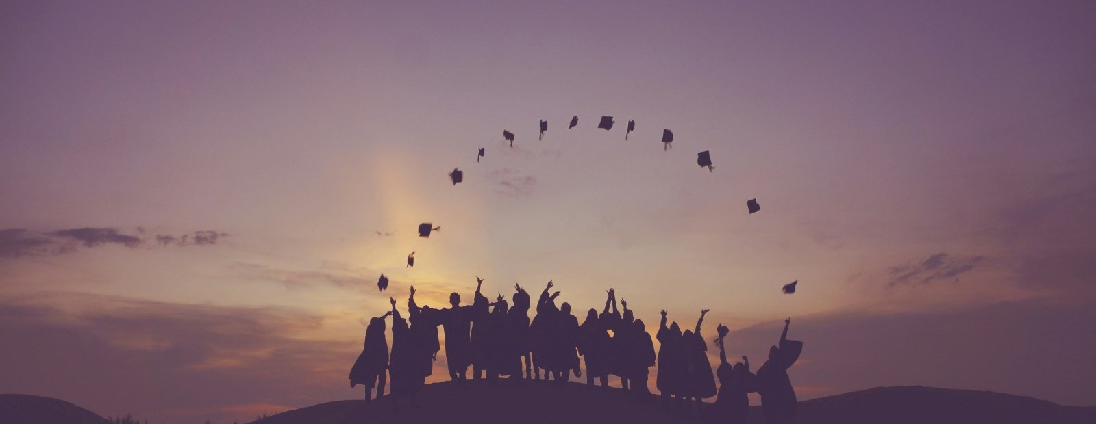 Students throwing grad caps in air. 